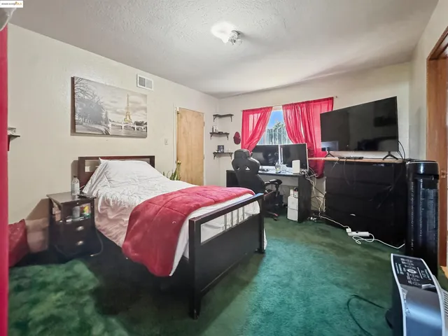 a spacious bedroom with a bed and a flat screen tv