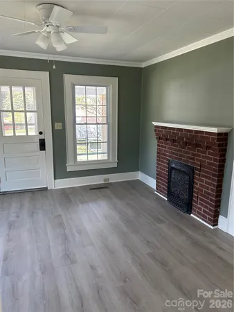 an empty room with wooden floor fireplace and windows