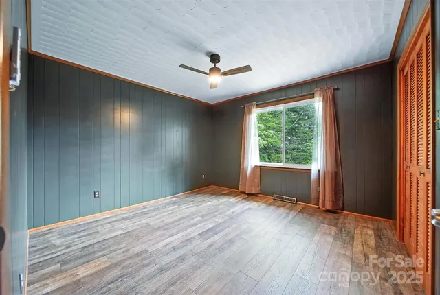 an empty room with wooden floor fan and windows