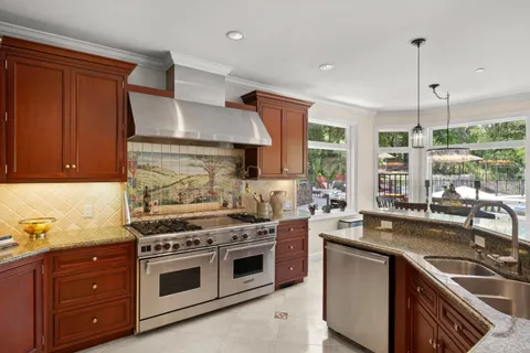 a kitchen with kitchen island granite countertop a sink a counter top space appliances and cabinets