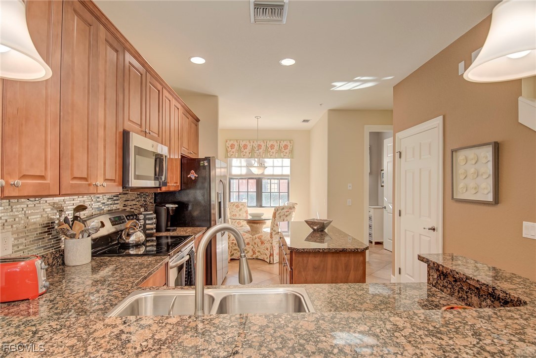 11856 Rocio Street, Unit 2003 Fort Myers, FL 33912 - Photo 5 of 43 a kitchen with stainless steel appliances granite countertop a sink a stove and a wooden cabinets