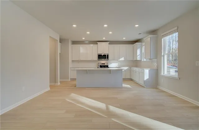 a view of kitchen with kitchen island a sink wooden floor and a refrigerator