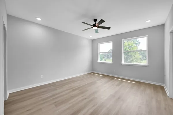 a view of empty room with wooden floor and fan