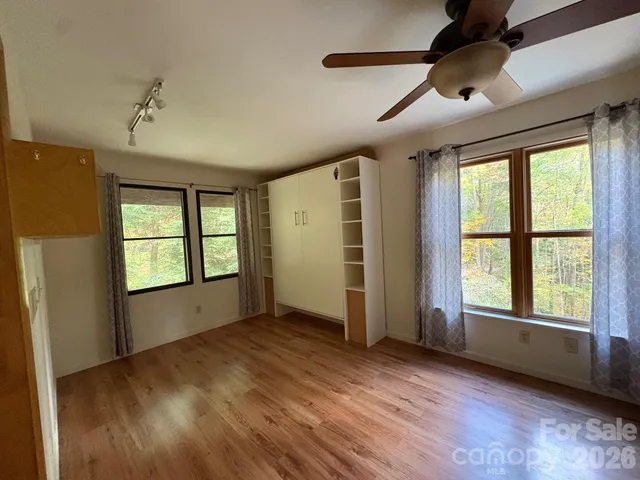 a view of an empty room with a window and wooden floor