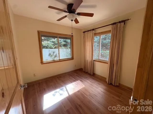 a view of an empty room with a window and wooden floor