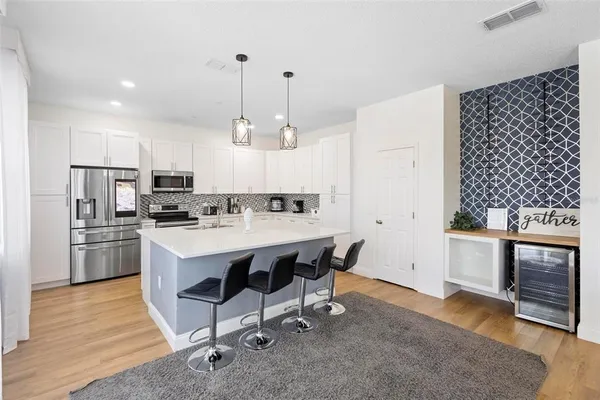 a kitchen with stainless steel appliances granite countertop a sink a stove a refrigerator and island with wooden floor