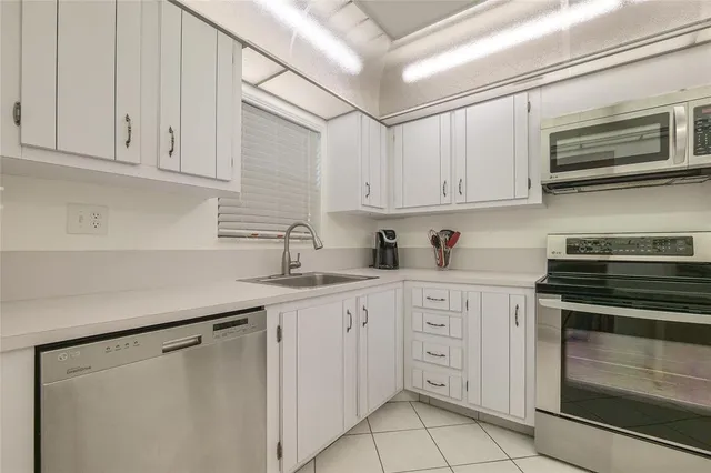 a kitchen with white cabinets and refrigerator