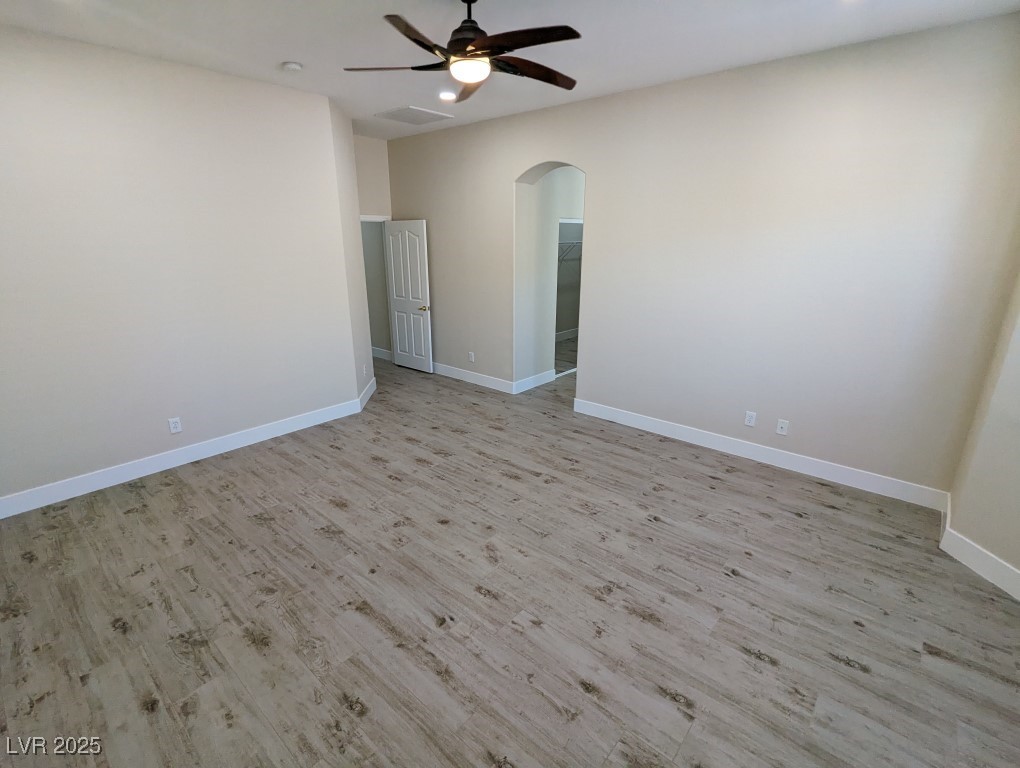 9976 Liberty View Road Las Vegas, NV 89148 - Photo 14 of 44 Spare room with light wood-type flooring, arched walkways, and ceiling fan