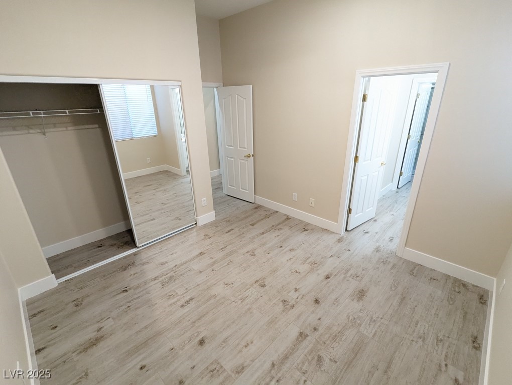 9976 Liberty View Road Las Vegas, NV 89148 - Photo 27 of 44 Unfurnished bedroom featuring a closet, light wood-style flooring, and a towering ceiling