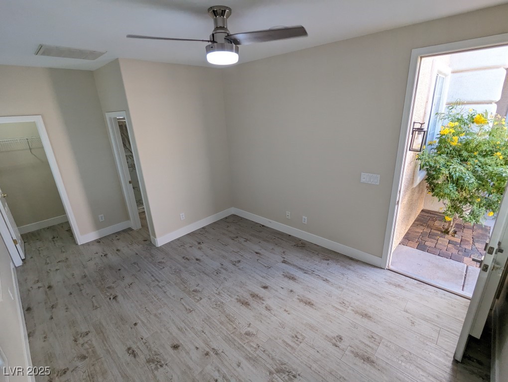 9976 Liberty View Road Las Vegas, NV 89148 - Photo 34 of 44 Unfurnished bedroom with a walk in closet, light wood-style floors, access to exterior, and a ceiling fan
