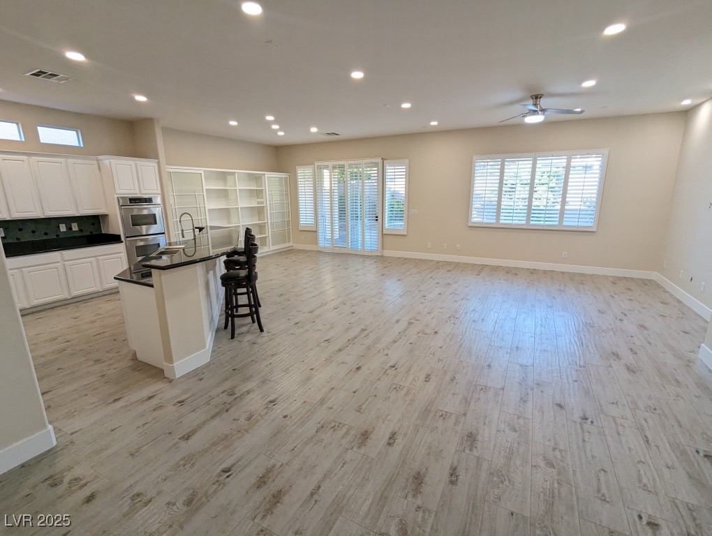 9976 Liberty View Road Las Vegas, NV 89148 - Photo 5 of 44 Kitchen featuring a kitchen breakfast bar, light wood finished floors, white cabinetry, healthy amount of natural light, and recessed lighting