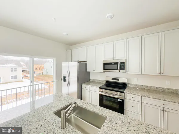 a kitchen with granite countertop a refrigerator stove and sink