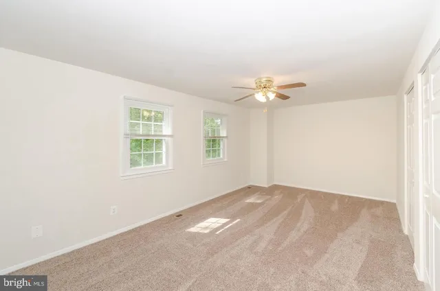 an empty room with a window and a fan