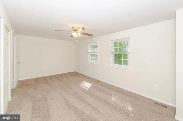 an empty room with windows and ceiling fan