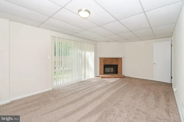 a view of an empty room with a fireplace and a window