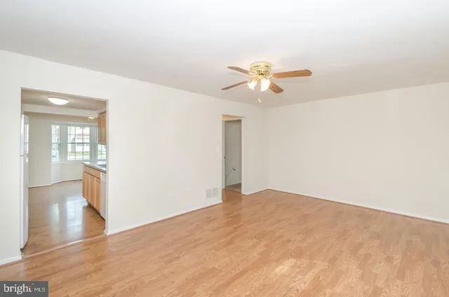 a view of a big room with wooden floor and a chandelier fan