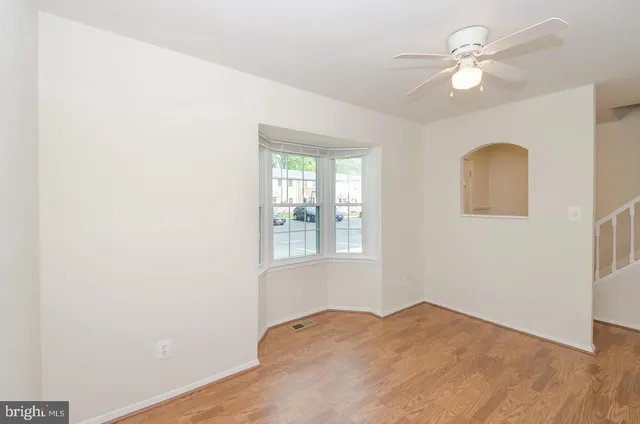 an empty room with windows and ceiling fan
