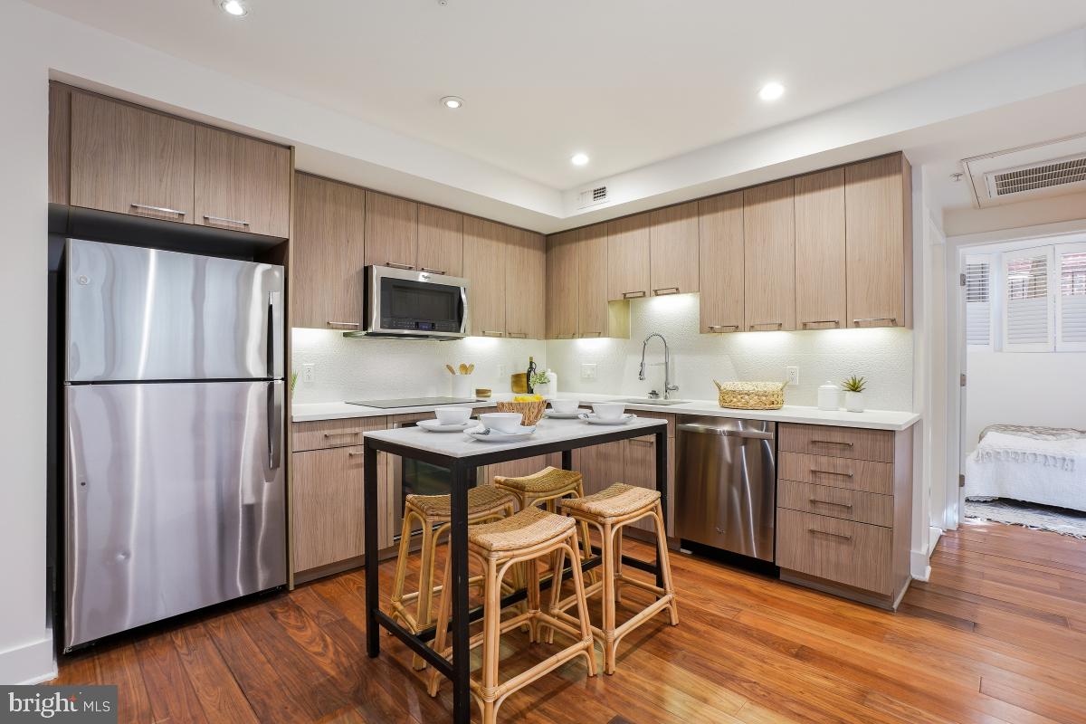 2331 15th Street Northwest, Unit 108N Washington, DC 20009 - Photo 1 of 25 a kitchen with stainless steel appliances granite countertop a refrigerator a sink dishwasher a stove with wooden cabinets and wooden floor