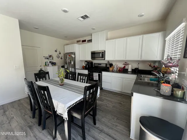 a kitchen with a dining table chairs and a refrigerator