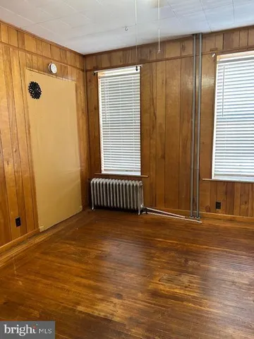 a view of a hallway with wooden floor and a bathroom