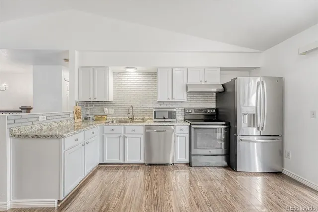 a kitchen with granite countertop white cabinets and white stainless steel appliances
