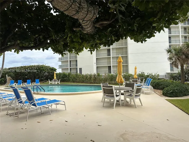 a view of a patio with a table and chairs under an umbrella with a small yard