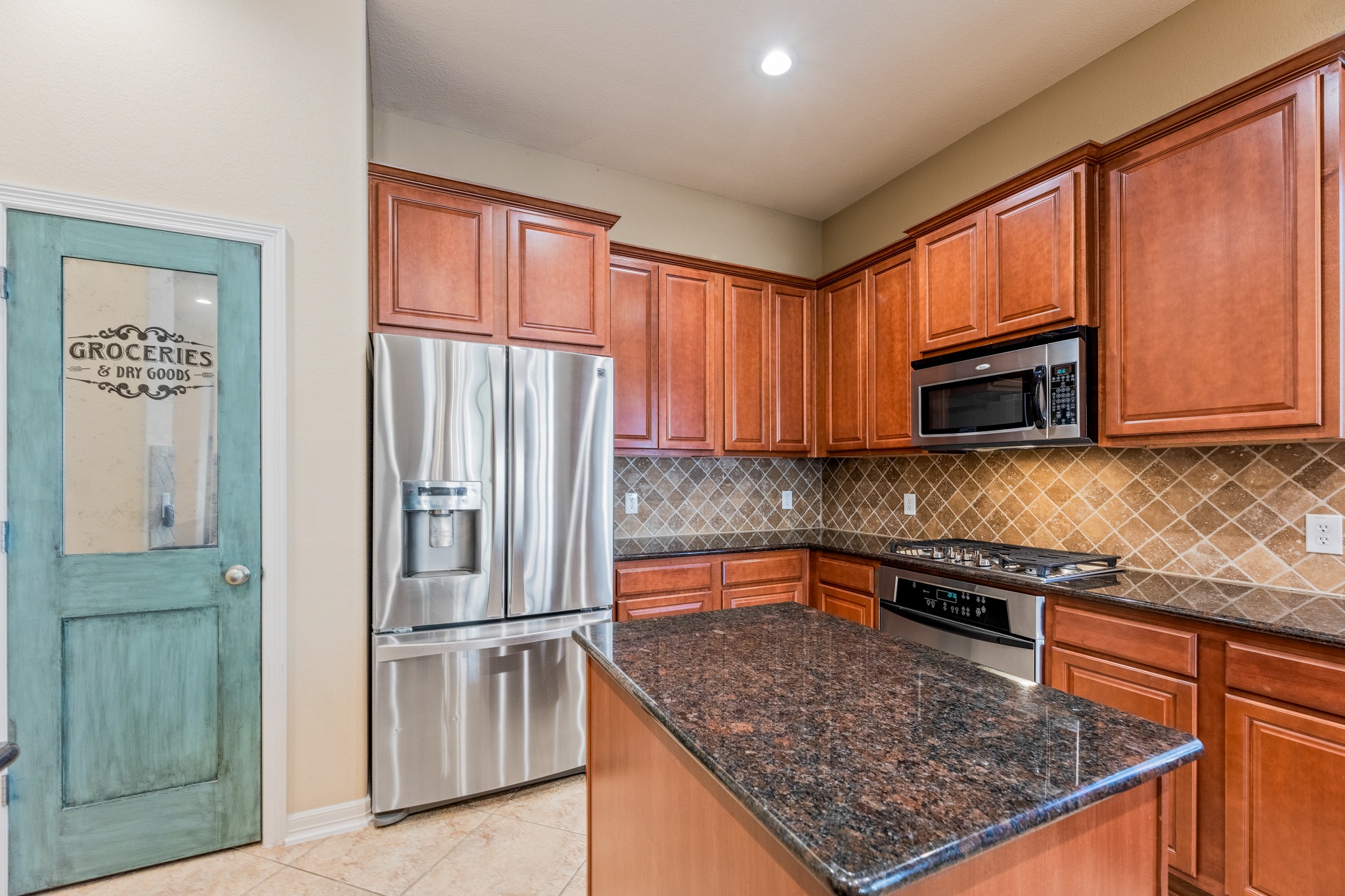 20804 Windmill Ridge Street Pflugerville, TX 78660 - Photo 11 of 40 Featuring a convenient center prep island, granite countertops, timeless cabinetry, and tiled backsplash.
