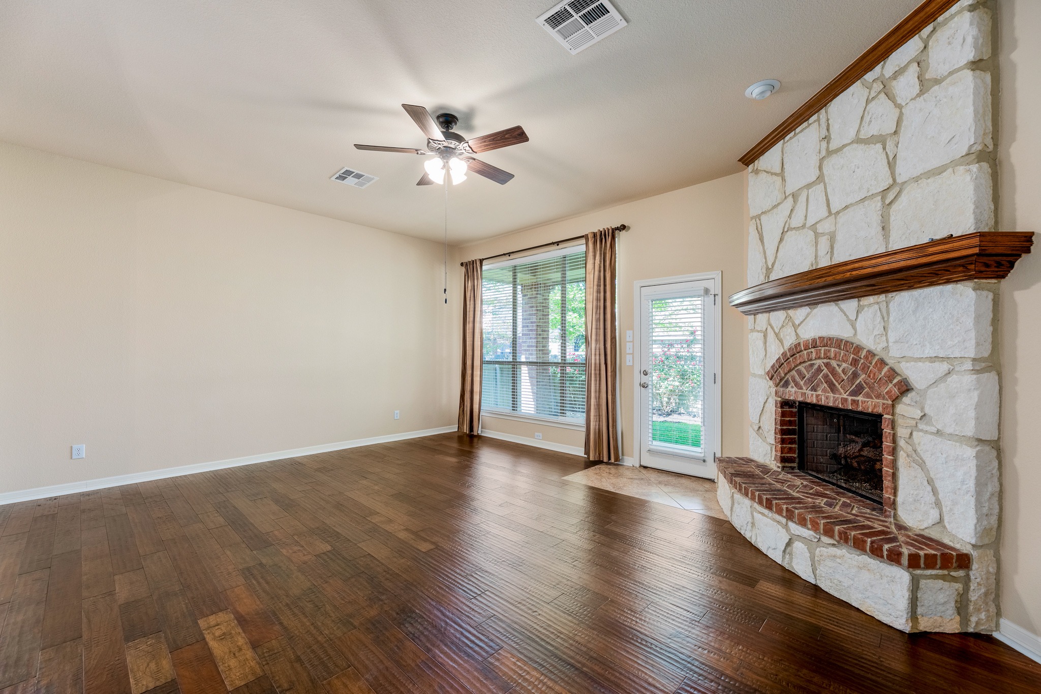 20804 Windmill Ridge Street Pflugerville, TX 78660 - Photo 8 of 40 Comfortable living with tall ceilings, hardwood floors, and a corner fireplace set in stone.