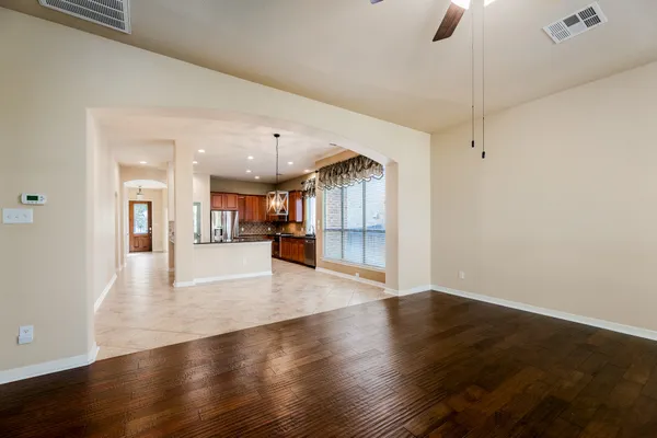 a kitchen with stainless steel appliances granite countertop a refrigerator a sink dishwasher a stove and a dining table with wooden floor