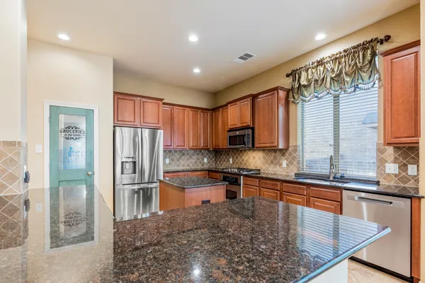 a kitchen with stainless steel appliances granite countertop a refrigerator a stove top oven a sink and dishwasher