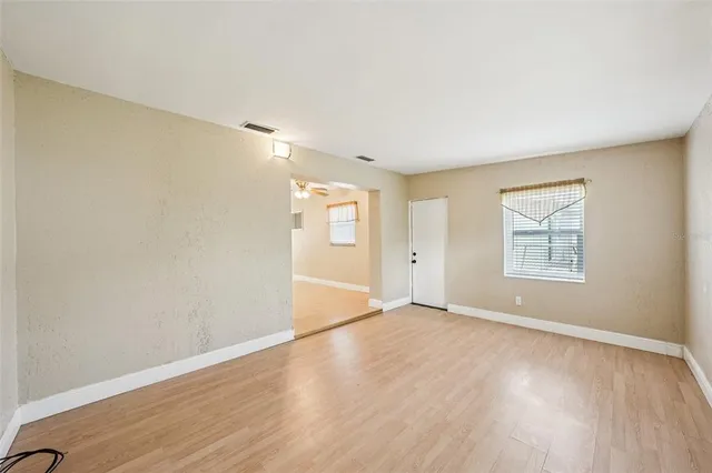 a view of an empty room with wooden floor and a window