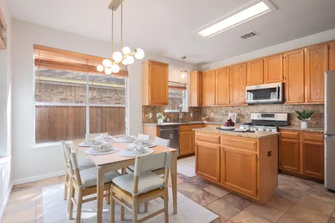 a kitchen with a stove a sink dishwasher a kitchen island with chairs and wooden cabinets