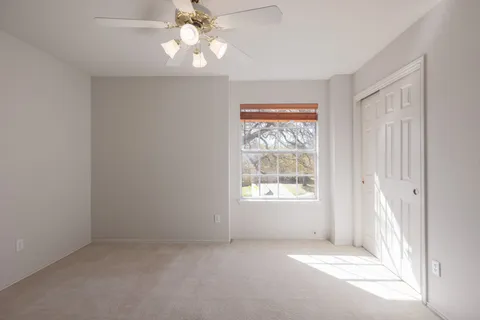 an empty room with a window and a fan