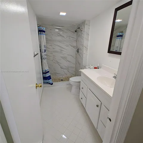 a bathroom with a granite countertop toilet sink mirror and vanity