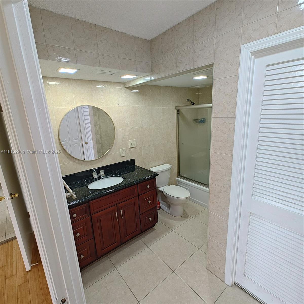 7051 Environ Boulevard, Unit 433 Lauderhill, FL 33319 - Photo 26 of 36 a bathroom with a granite countertop toilet sink mirror and vanity