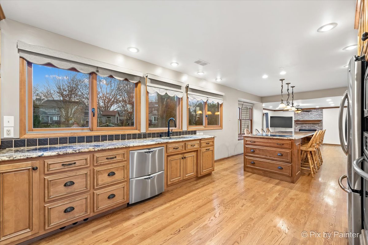 562 Boardman Circle Bolingbrook, IL 60440 - Photo 16 of 47 a kitchen with stainless steel appliances kitchen island granite countertop a stove a sink a refrigerator and white cabinets with wooden floor
