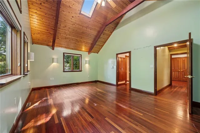 a view of an empty room with wooden floor and windows
