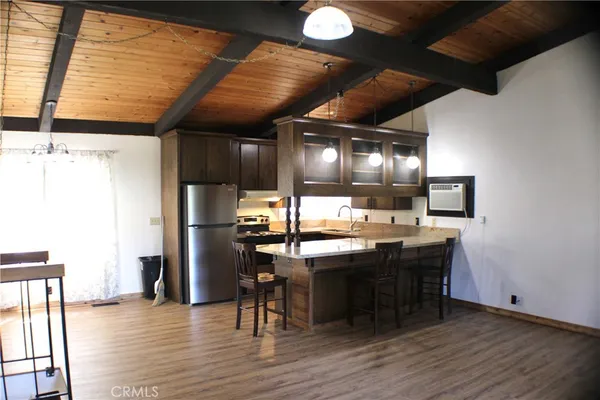 a room with stainless steel appliances kitchen island granite countertop a table chairs and a refrigerator