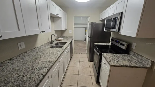 a kitchen with granite countertop stainless steel appliances a sink stove and refrigerator