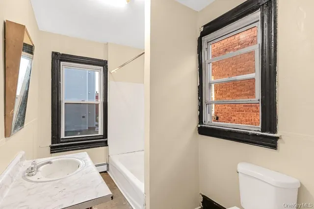a bathroom with a granite countertop sink toilet and mirror