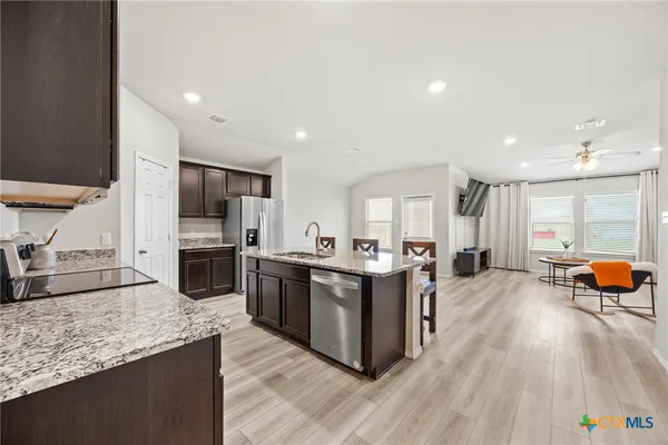 a kitchen with stainless steel appliances granite countertop lots of counter top space and wooden floor