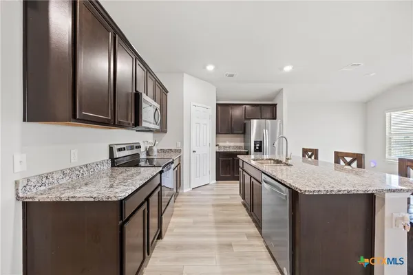a view of kitchen island with granite countertop refrigerator stove dining table and chairs