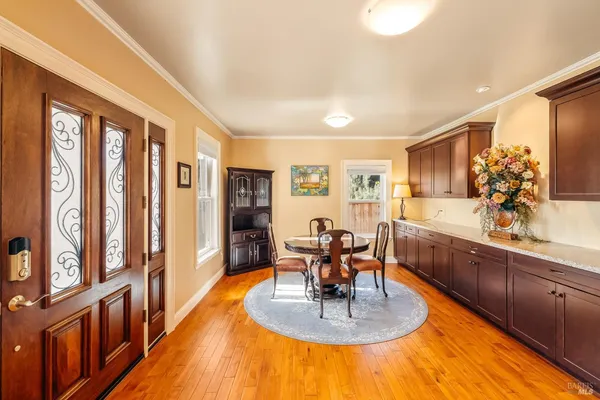 a large living room with large couches chandelier and a dining table with wooden floor