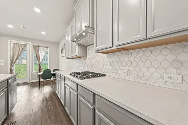 a kitchen with a sink a stove cabinets and wooden floor