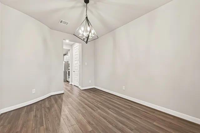 a view of empty room with wooden floor and chandelier