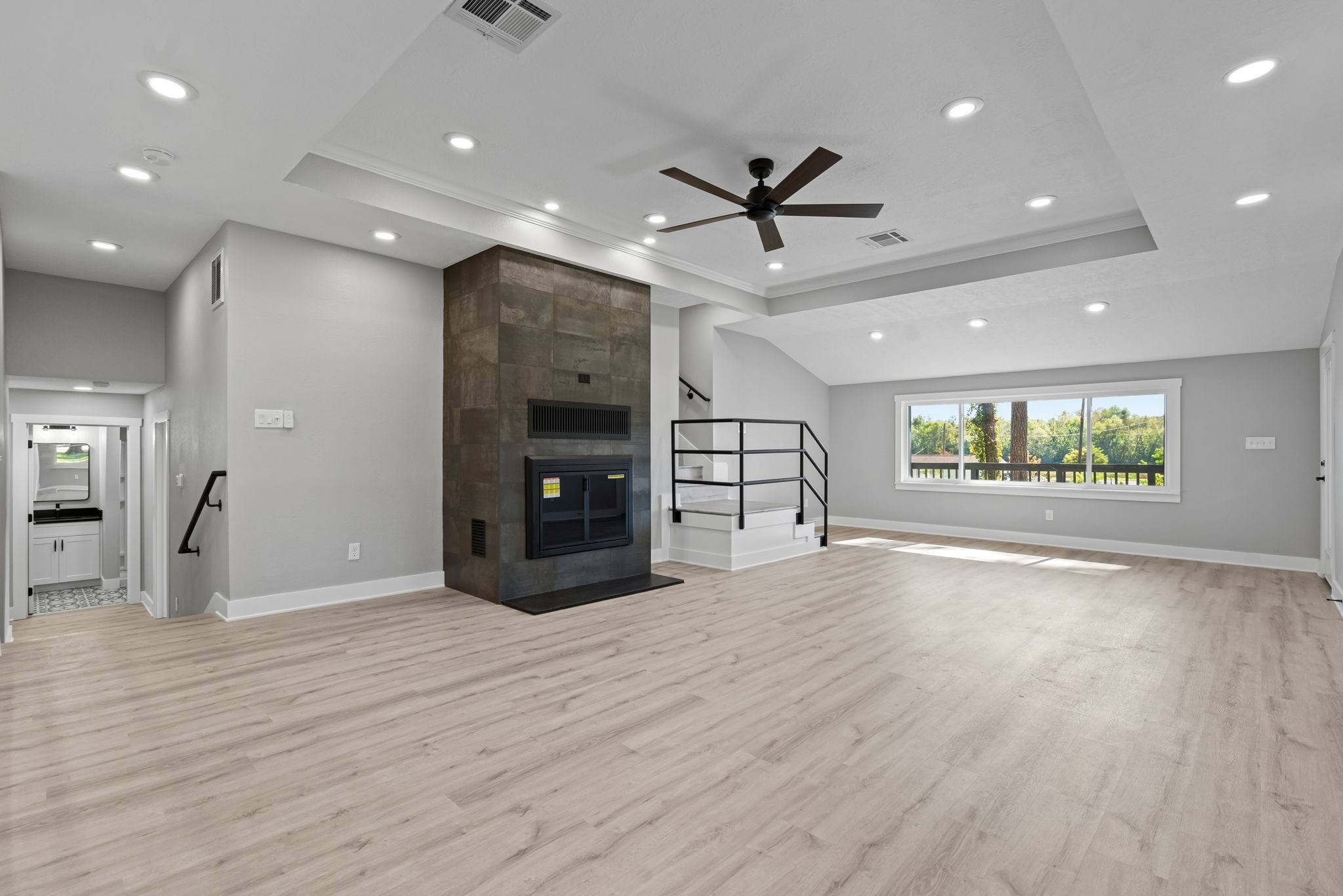 284 Hackberry Street Trinity, TX 75862 - Photo 10 of 42 The sunken living room area features a tiered ceiling, updated LED lighting a dramatic fireplace with granite hearth and modern tile surround, and updated luxury vinyl plank flooring.