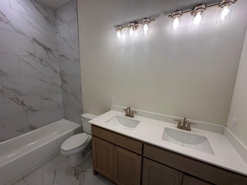 205 Cobb Road Leonard, TX 75452 - Photo 23 of 28 Bathroom featuring a dual vanity with rectangular undermount sinks and bronze-finish faucets, a white countertop, and wood-finish cabinetry