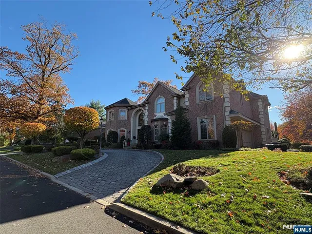 a large tree in front of a brick house next to a yard