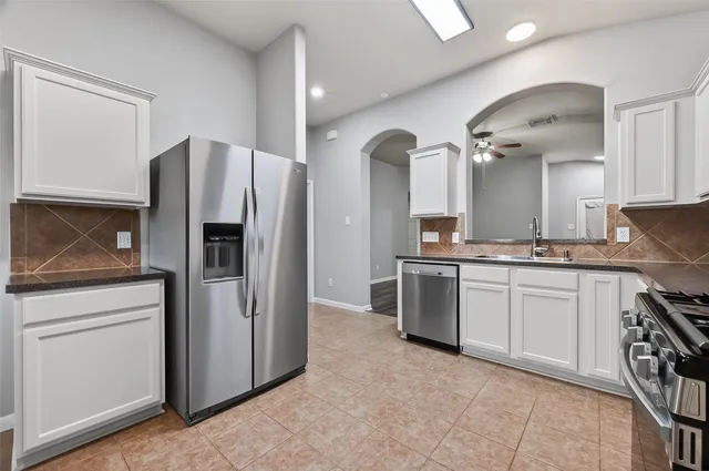 a kitchen with stainless steel appliances granite countertop a refrigerator a stove and a sink