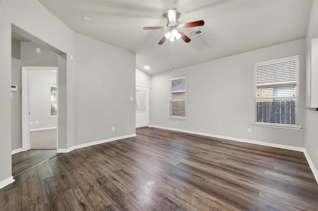 a view of an empty room with a window and wooden floor